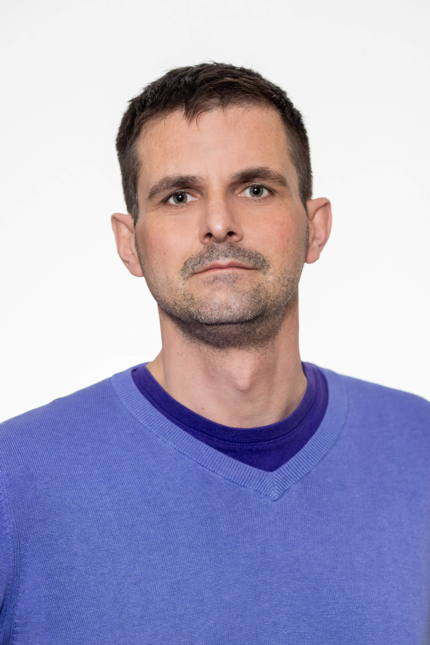 Herr Sandhofer trägt blaues V‑Ausschnitt‑Pullover und T‑Shirt, Killer Entsorungsfirma