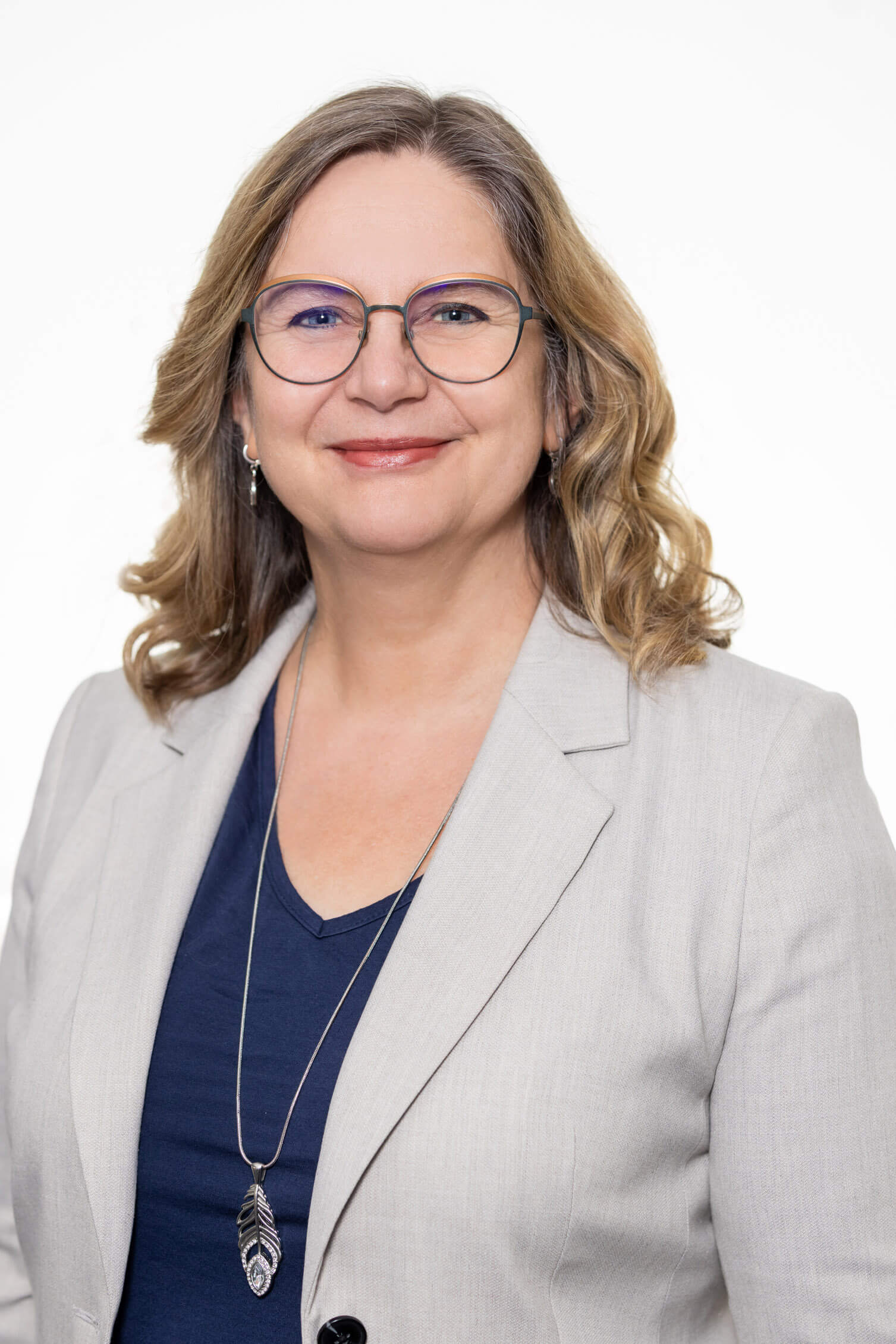 Frau Scholz mit Brille, hellgrauem Blazer und Anhänger in Form einer Feder, Killer Entsorungsfirma